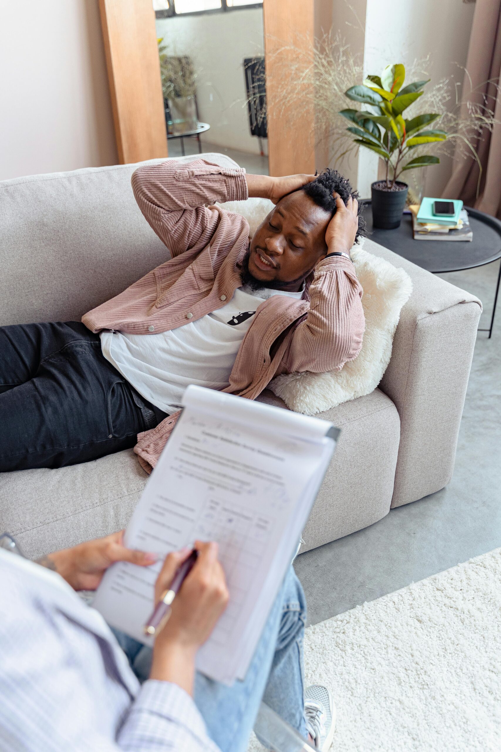 Man in therapy laying on couch holding his head.